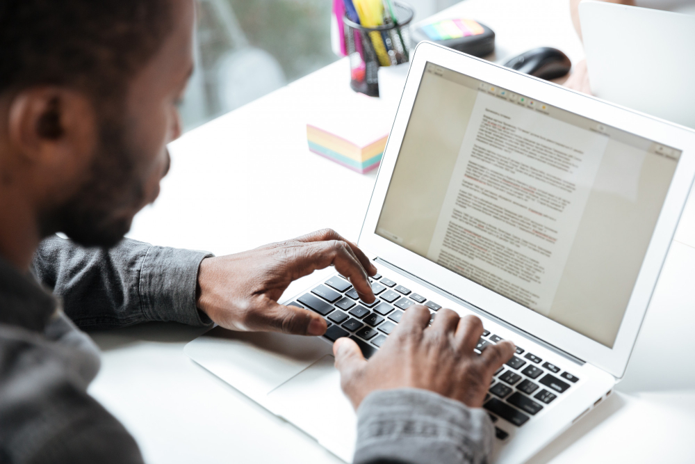 kobi education-jenis-jenis essay untuk study abroad-gambar orang sedang mengetik essay di laptop warna putih