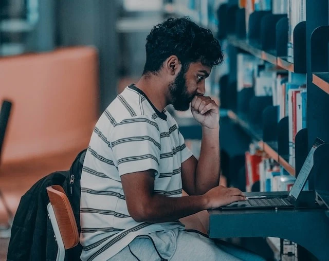 kobi education-persiapan ielts berapa lama-gambar orang sedang mengerjakan tugas di laptop dalam ruang perpustakaan