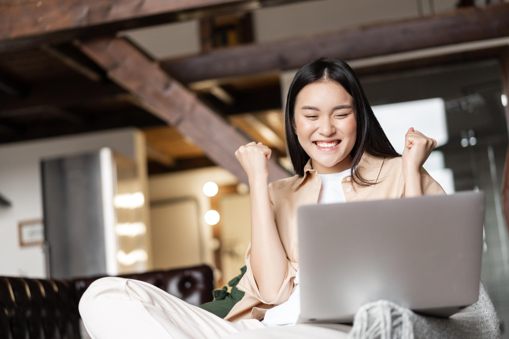 kobi education-beasiswa kuliah 2024-gambar wanita sedang gembira ketika melihat video di laptopnya