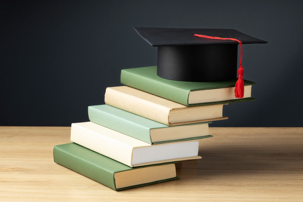 kobi education-beasiswa luar negeri 2024-gambar tumpukan buku dan diatas buku terakhir adalah topi wisuda