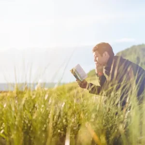 kobi education-jurusan luar negeri-gambar pria sedang membaca buku di tengah ladang