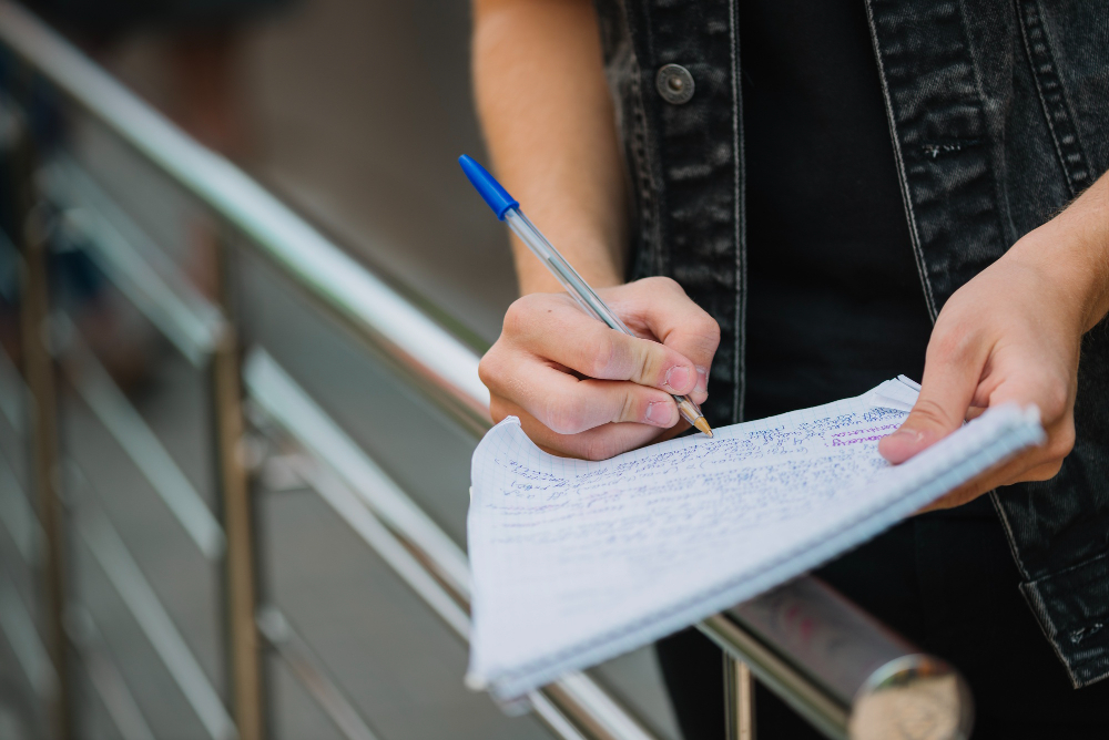 kobi education-contoh soal toefl ibt-gambar orang sedang menulis sesuatu di atas kertas putih dengan penuh semangat