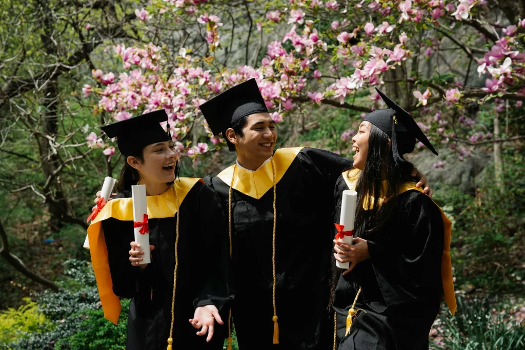 kobi education-program double degree-gambar tiga wisudawan yang sedang berbicara di tengah taman