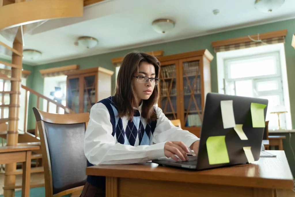 kobi education-contoh essay beasiswa luar negeri-gambar kedua perempuan sedang mengerjakan tugas proyek lewat laptop dirumahnya secara nyaman