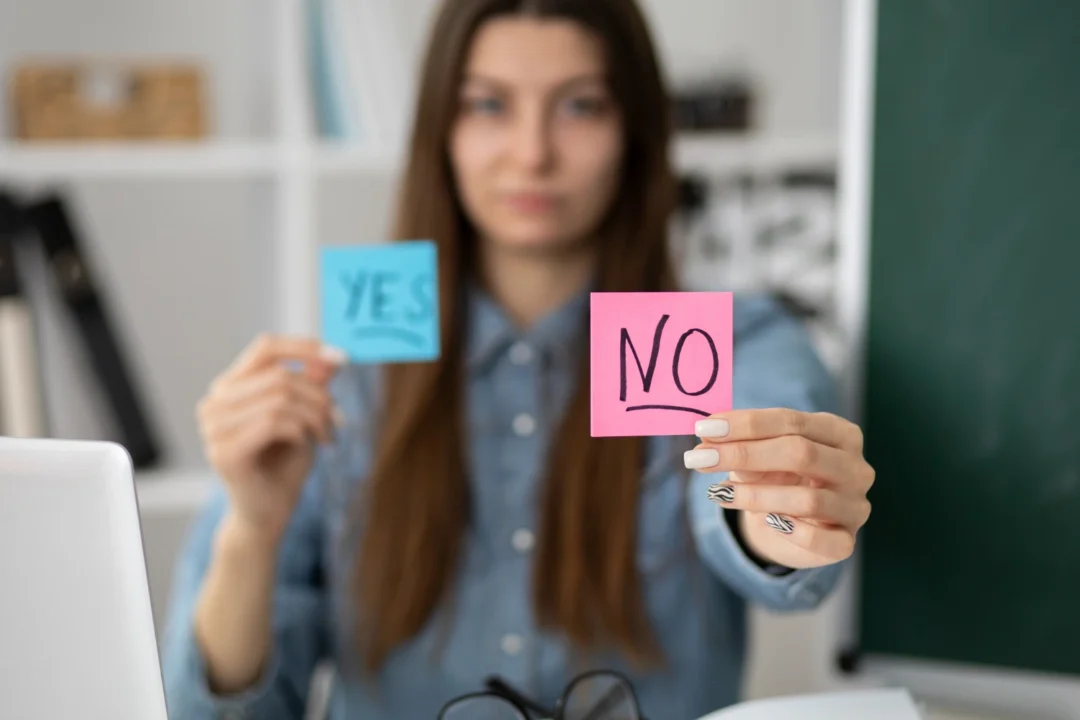 kobi education-kesalahan belajar grammar-gambar perempuan sedang memegang kertas biru dan kertas pink yang memberikan kata yes serta no