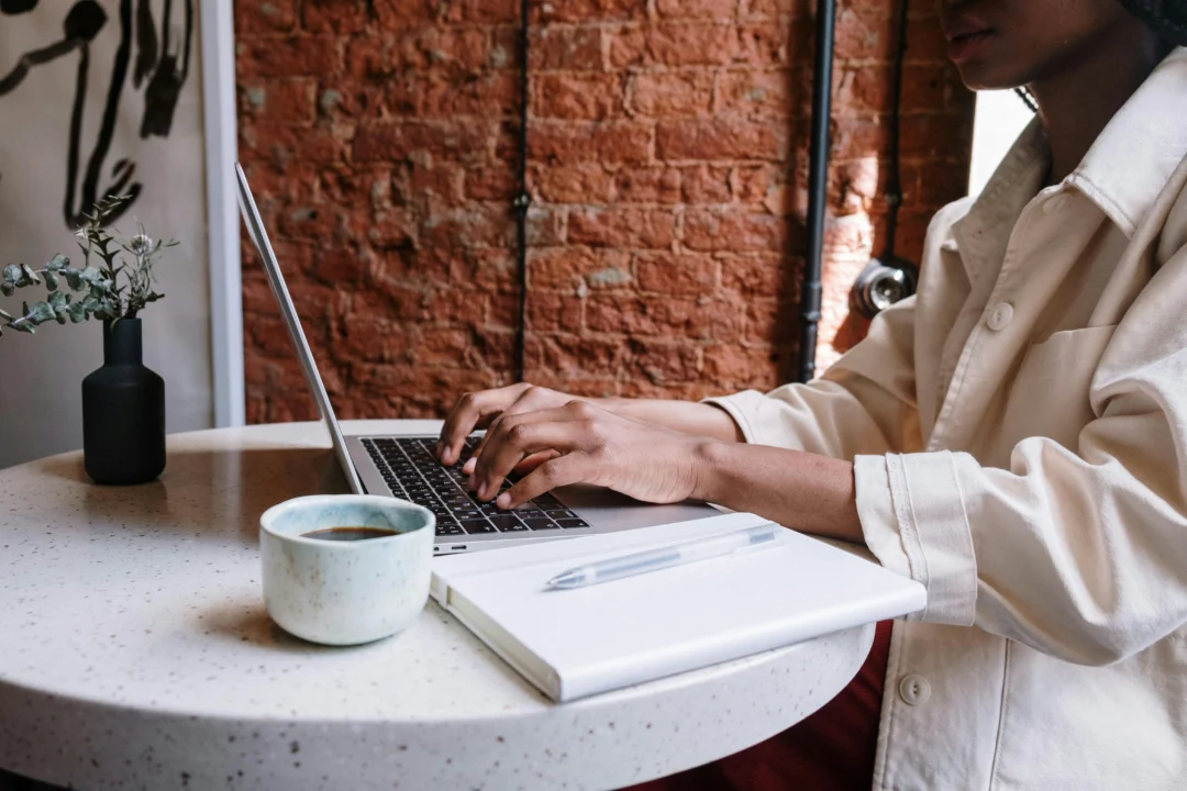 kobi education-cara menangani plagiarism yang ga disengaja-gambar seseorang sedang fokus mengerjakan projek tulisan melalui laptopnya di dalam ruangan kafe tertentu