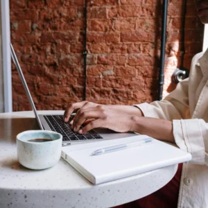 kobi education-cara menangani plagiarism yang ga disengaja-gambar seseorang sedang fokus mengerjakan projek tulisan melalui laptopnya di dalam ruangan kafe tertentu