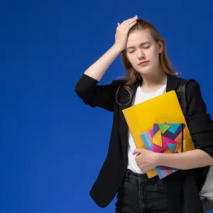 kobi education-cara memilih jalur lpdp-gambar perempuan sedang pusing dalam menghadapi pekerjaannya dengan background biru dibelakangnya