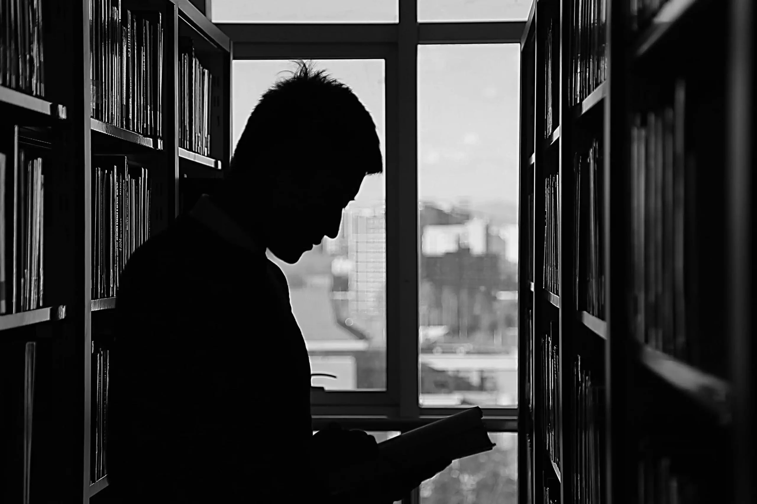 kobi education-universitas terbaik di belanda-gambar bayangan seseorang sedang membaca buku di tengah cuaca yang cukup gelap