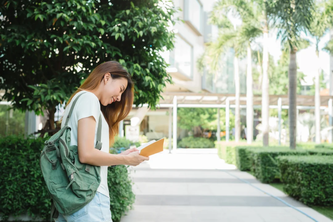 kobi education-beasiswa s2 denmark-gambar perempuan sedang membaca panduan wisata via buku kecil berwarna kuning