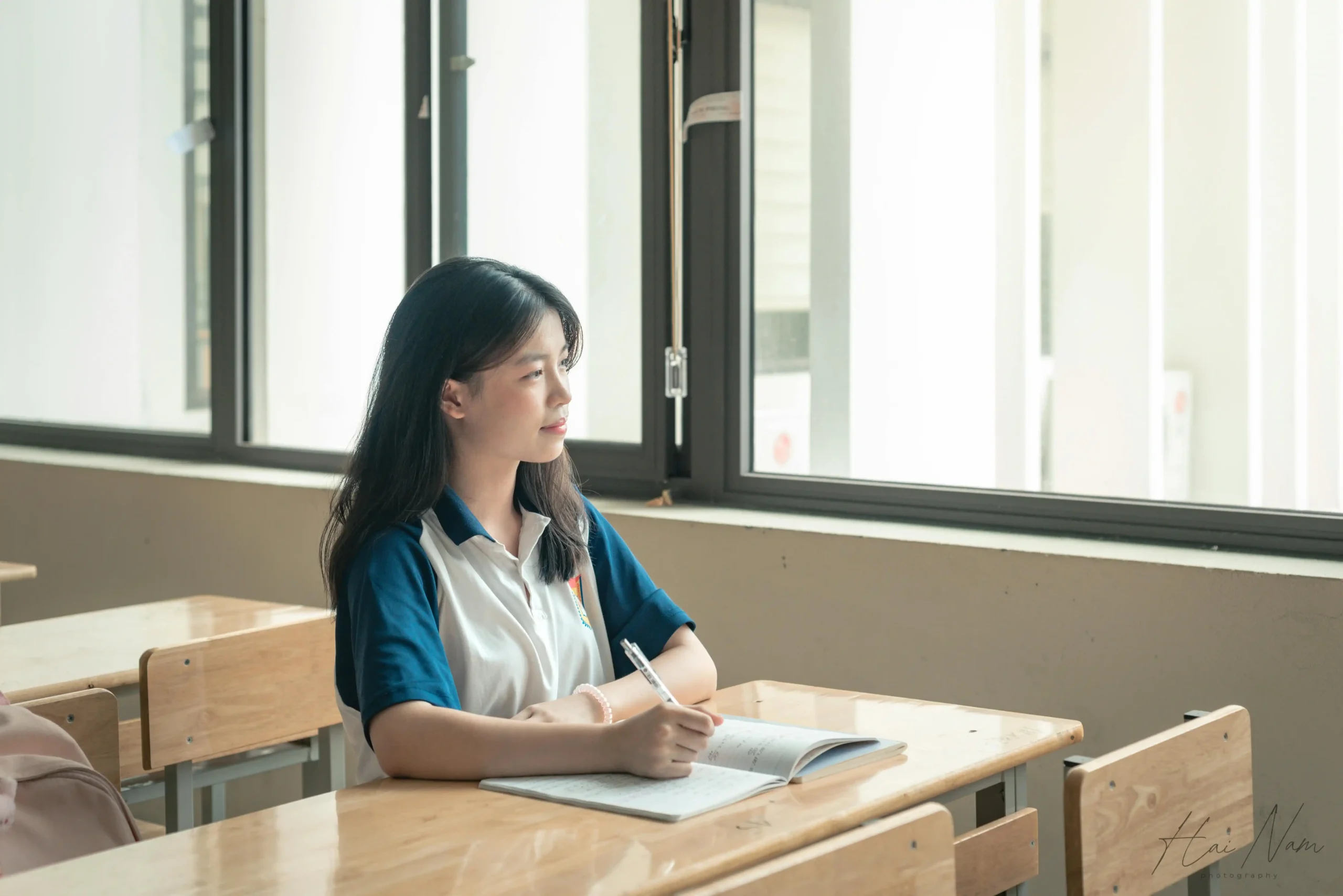 kobi education-universitas fudan-gambar mahasiswi sedang memikirkan peluang yang ia dapatkan di tengah ruang kelas yang cerah
