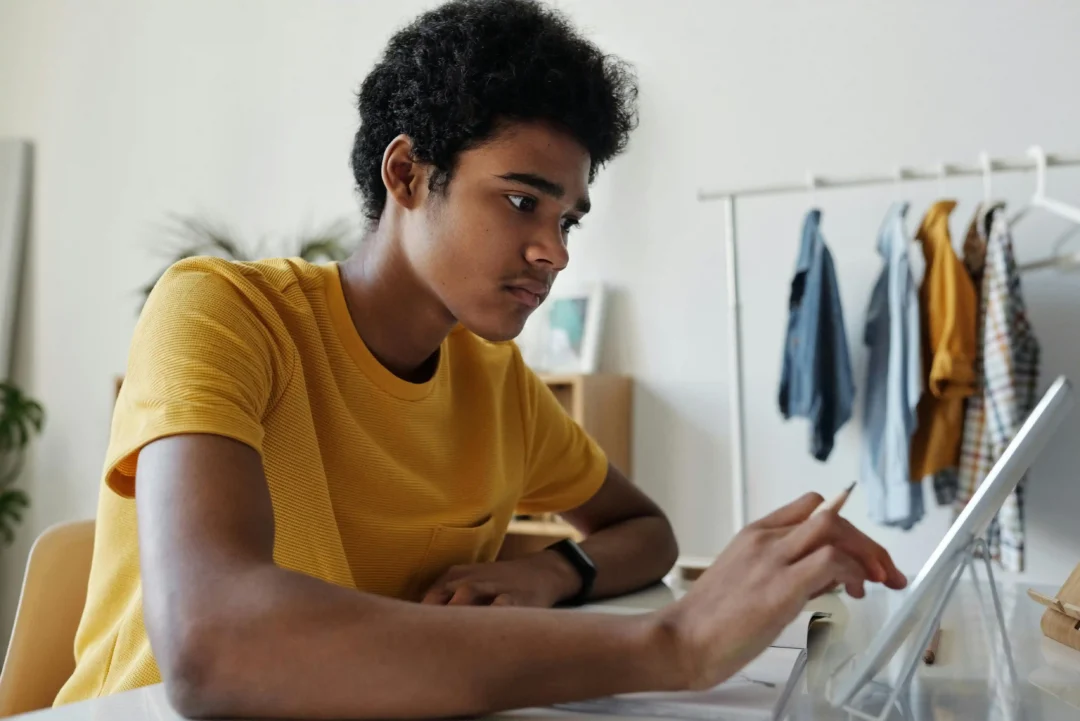kobi education-daftar universitas luar negeri yang meminta sat-gambar pria dari negara luar dengan menggunakan kaos kuning sedang mengerjakan tugas pekerjaannya secara serius via online