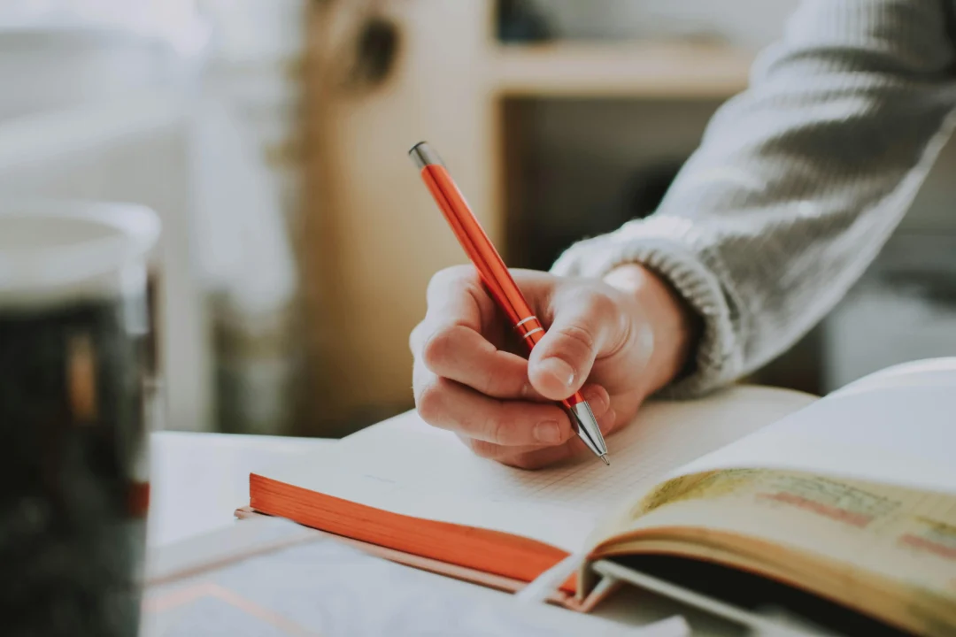 kobi education-contoh essay chevening-gambar seseorang sedang menulis dengan pulpen elektronik berwarna orange