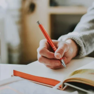 kobi education-contoh essay chevening-gambar seseorang sedang menulis dengan pulpen elektronik berwarna orange