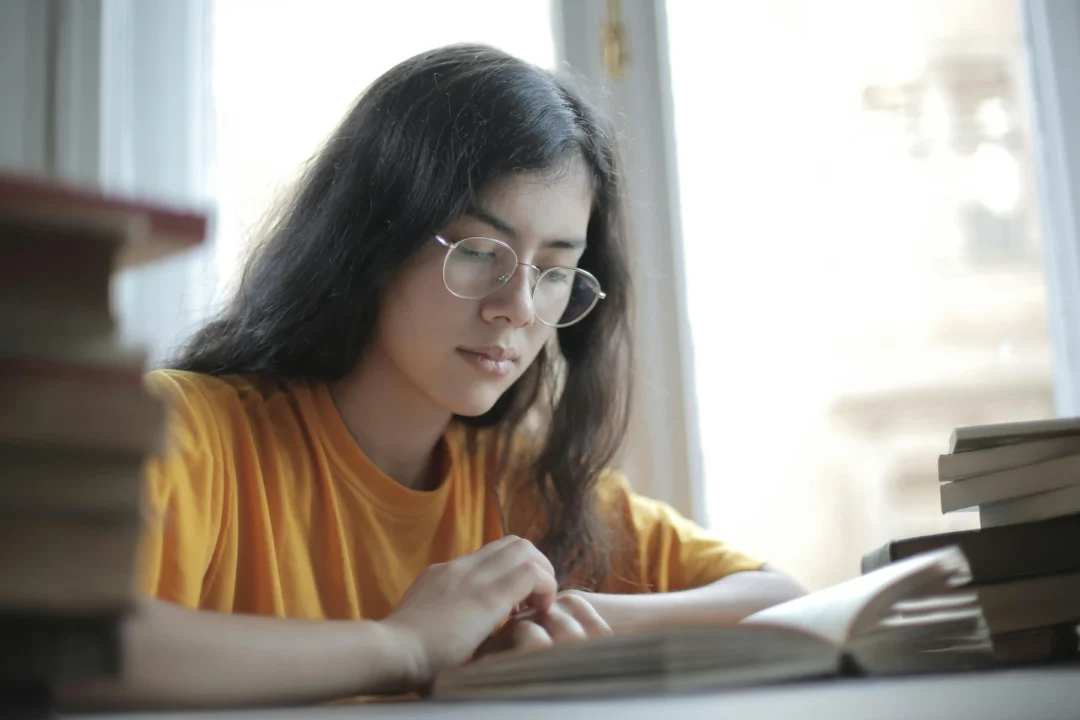kobi education-perbedaan sat subject test dan sat general-gambar mahaisiswi yang sedang menggunakan kacamata belajar dengan sangat serius di siang hari