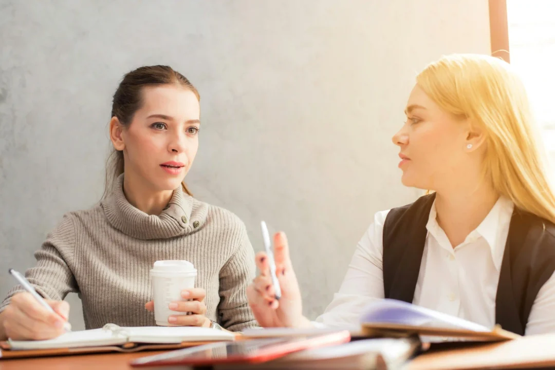 kobi education-skrip untuk latihan belajar speaking ielts-gambar dua wanita sedang berdiskusi mengenai suatu bisnis di tengah matahari yang cerah