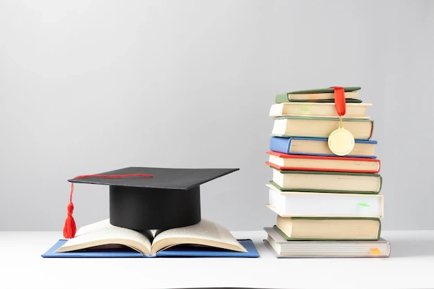 kobi education-beasiswa taiwan-gambar tumpukan buku yang berdiri di samping topi toga