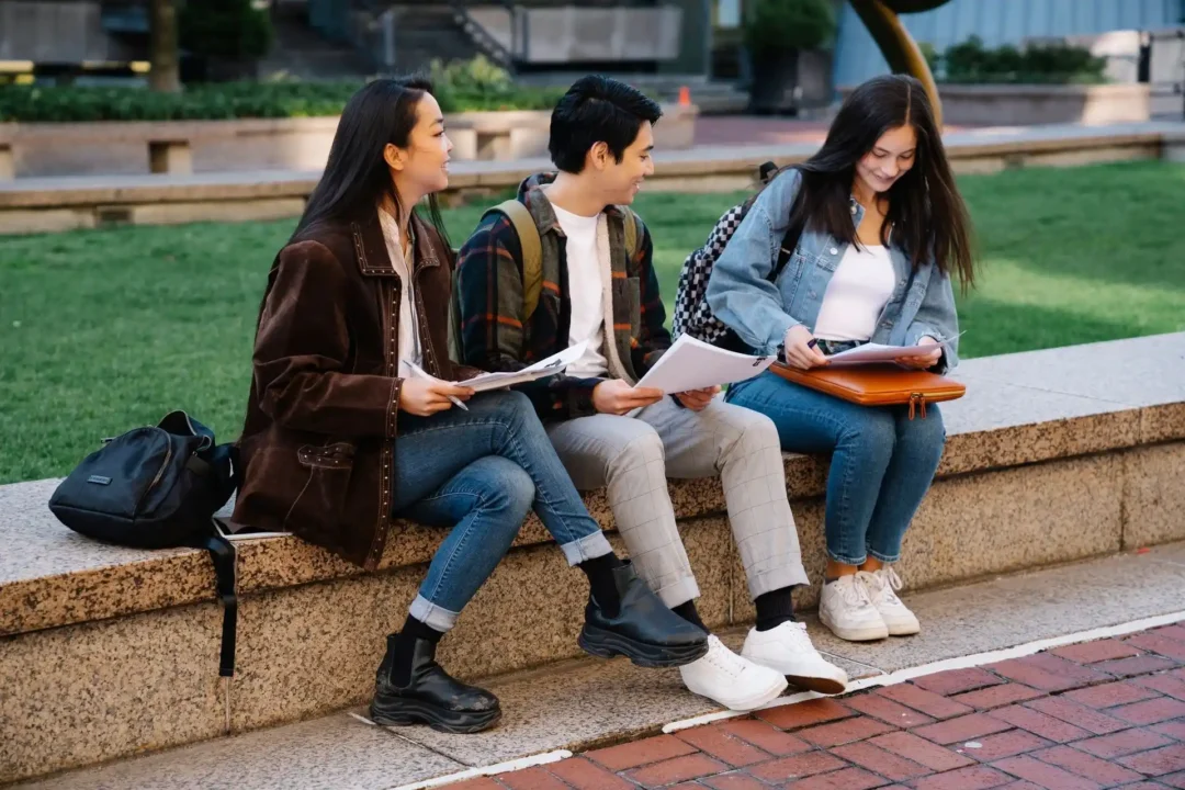 kobi education-tips memilih universitas luar negeri-gambar tiga mahasiswa internasional yang sedang duduk bersama dan membahas mengenai projek yang mereka kerjakan