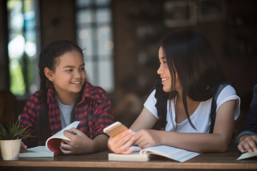 kobi education-program student exchange sma amerika-gambar ilustrasi dua orang wanita yang sedang membahas suatu topik secara santai di perpustakaan